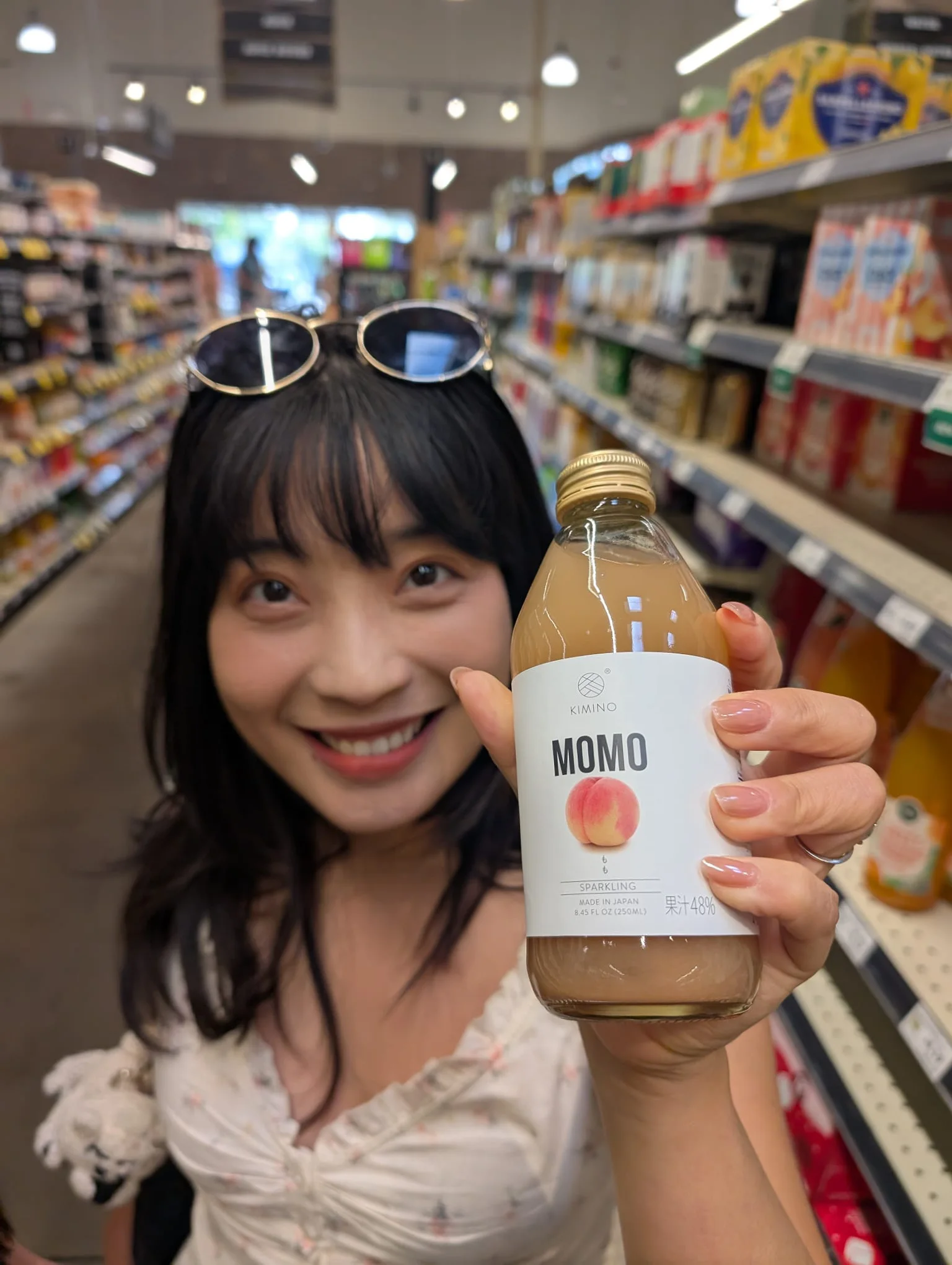 Mengmeng holding a peach soda in a grocery store