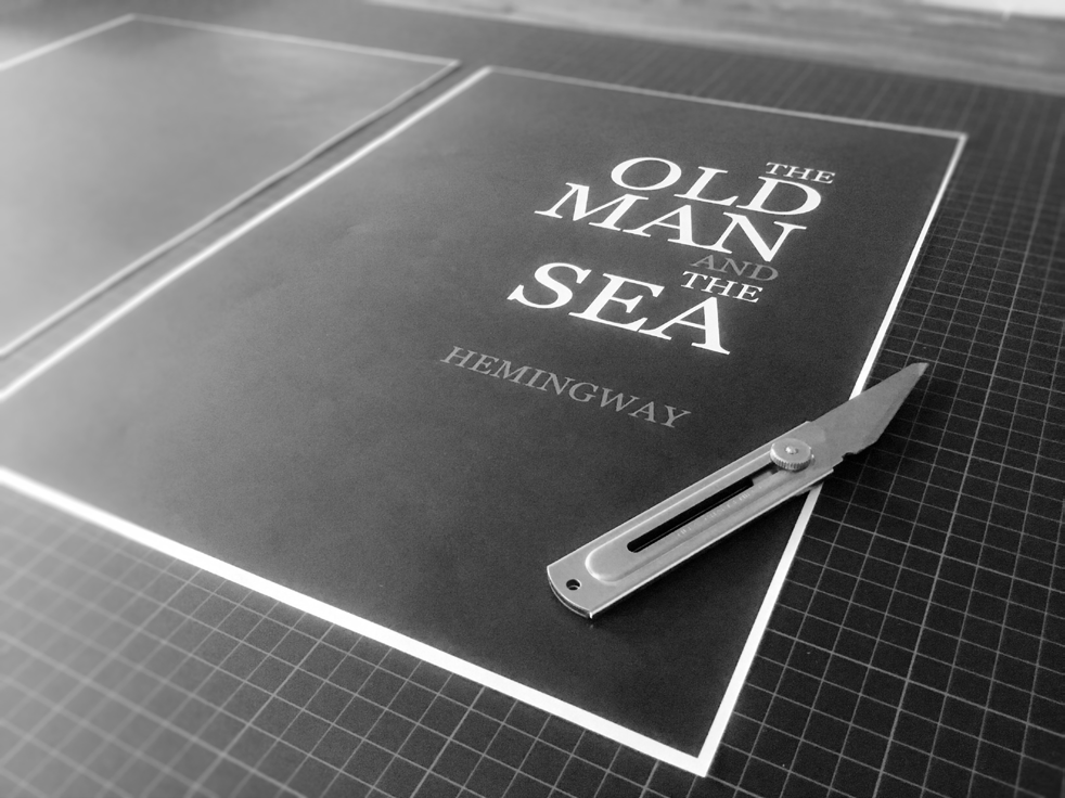Printed cover artwork being trimmed with a utility knife