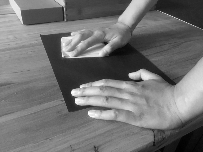 Hands polishing a dark sheet of cover material